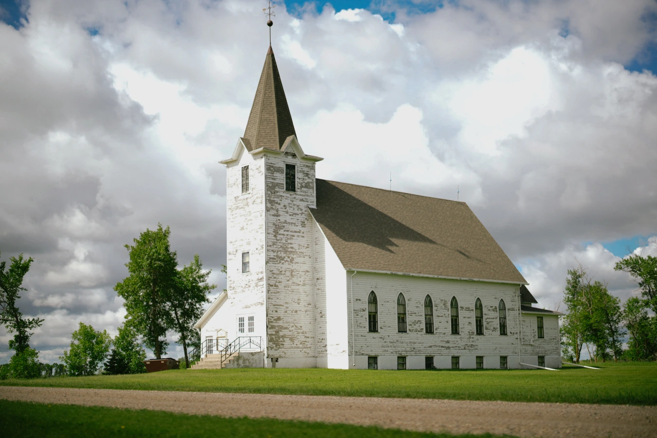 White church steeple cloudy sky at Amy and Teddy's North Dakota farm wedding by Megaset Weddings