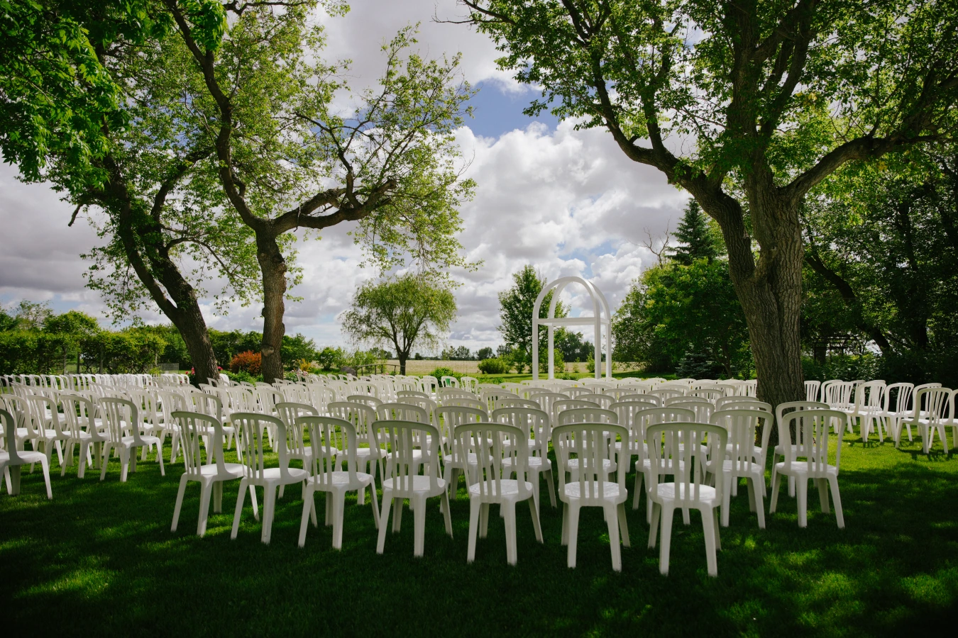 Outdoor chairs tree arch at Amy and Teddy's North Dakota farm wedding by Megaset Weddings