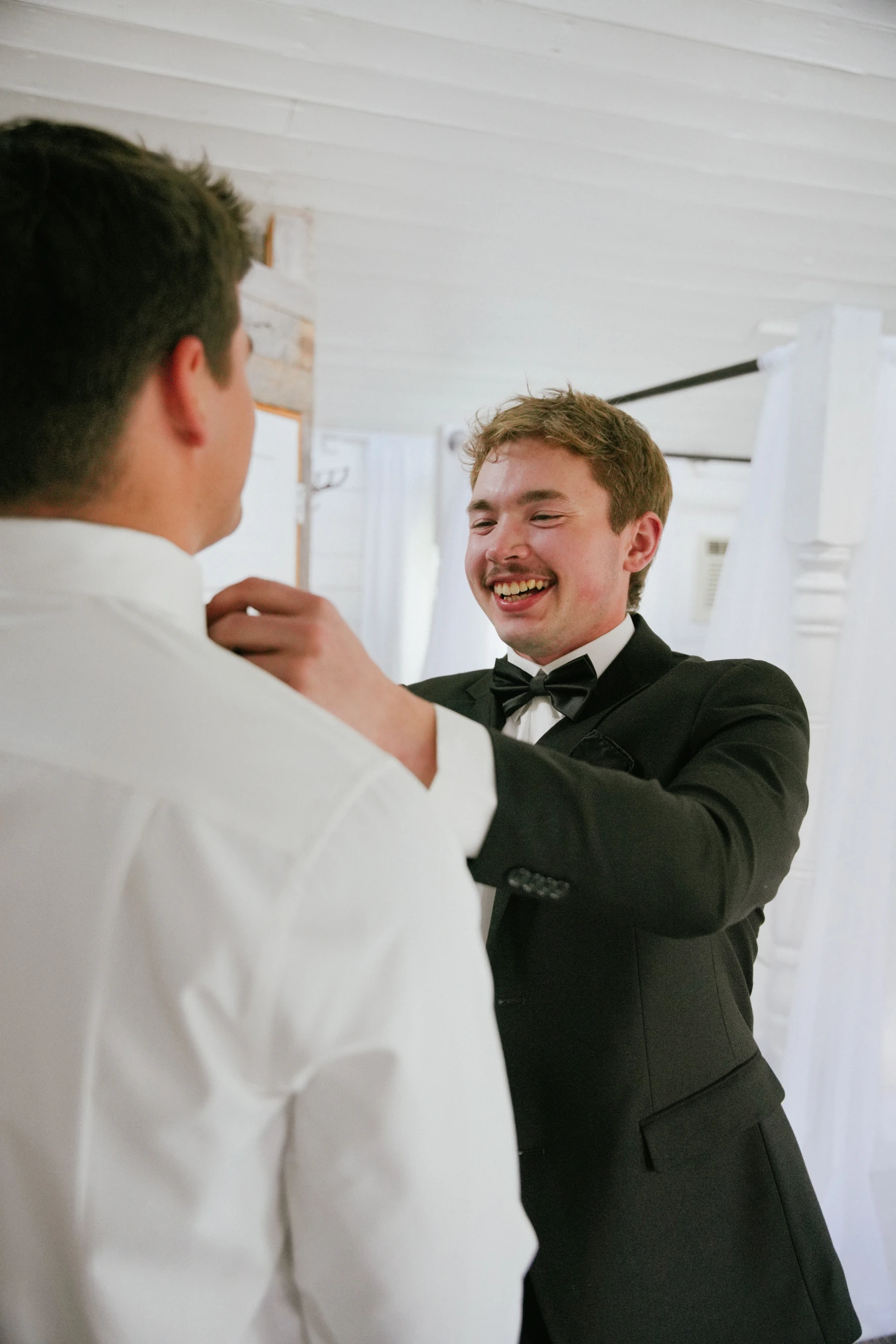 Teddysman adjusting teddy bow tie smiling at Amy and Teddy's North Dakota farm wedding by Megaset Weddings