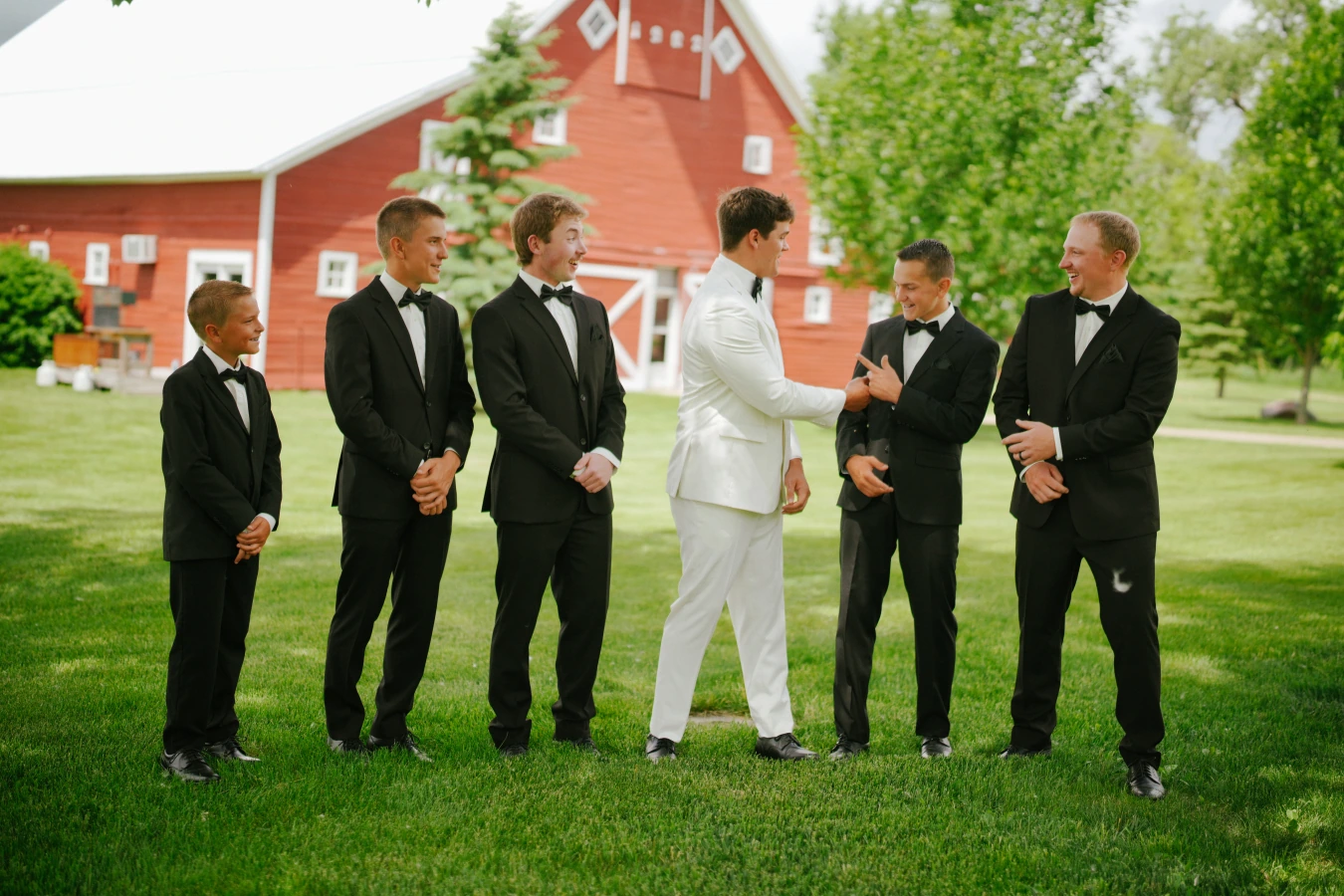 Teddy in his white suit teddysmen black suits outdoor barn at Amy and Teddy's North Dakota farm wedding by Megaset Weddings