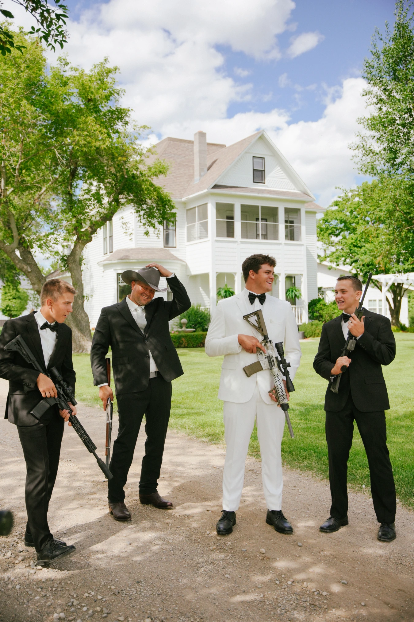 Teddy in his white suit teddysmen black suits rifles portrait at Amy and Teddy's North Dakota farm wedding by Megaset Weddings
