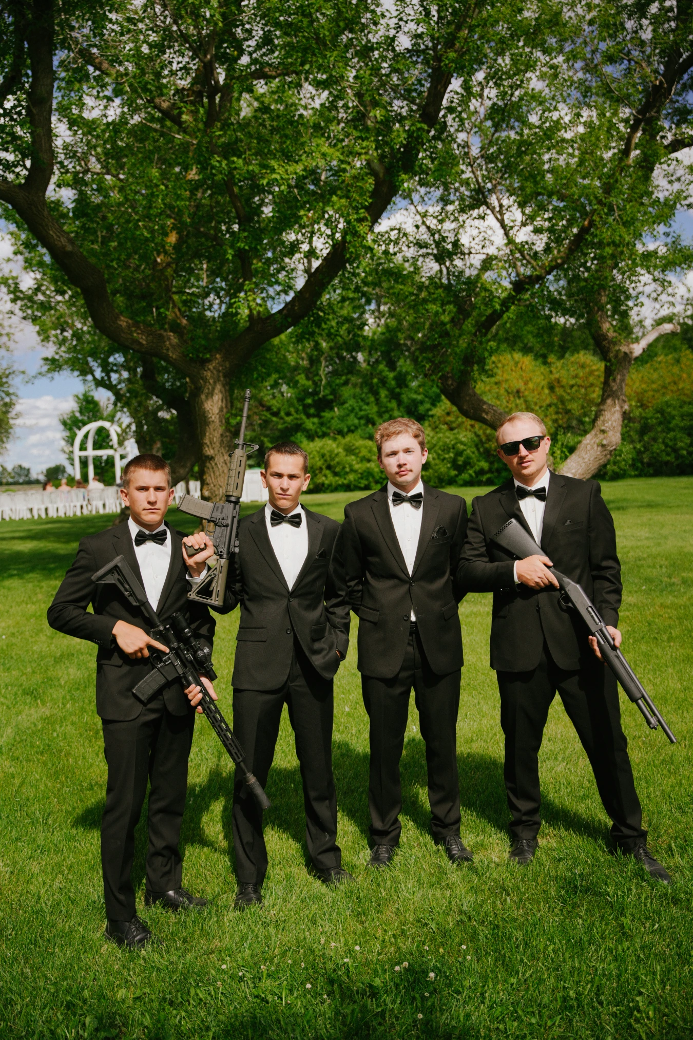 Teddy in his white suit teddysmen black suits rifles outdoor at Amy and Teddy's North Dakota farm wedding by Megaset Weddings