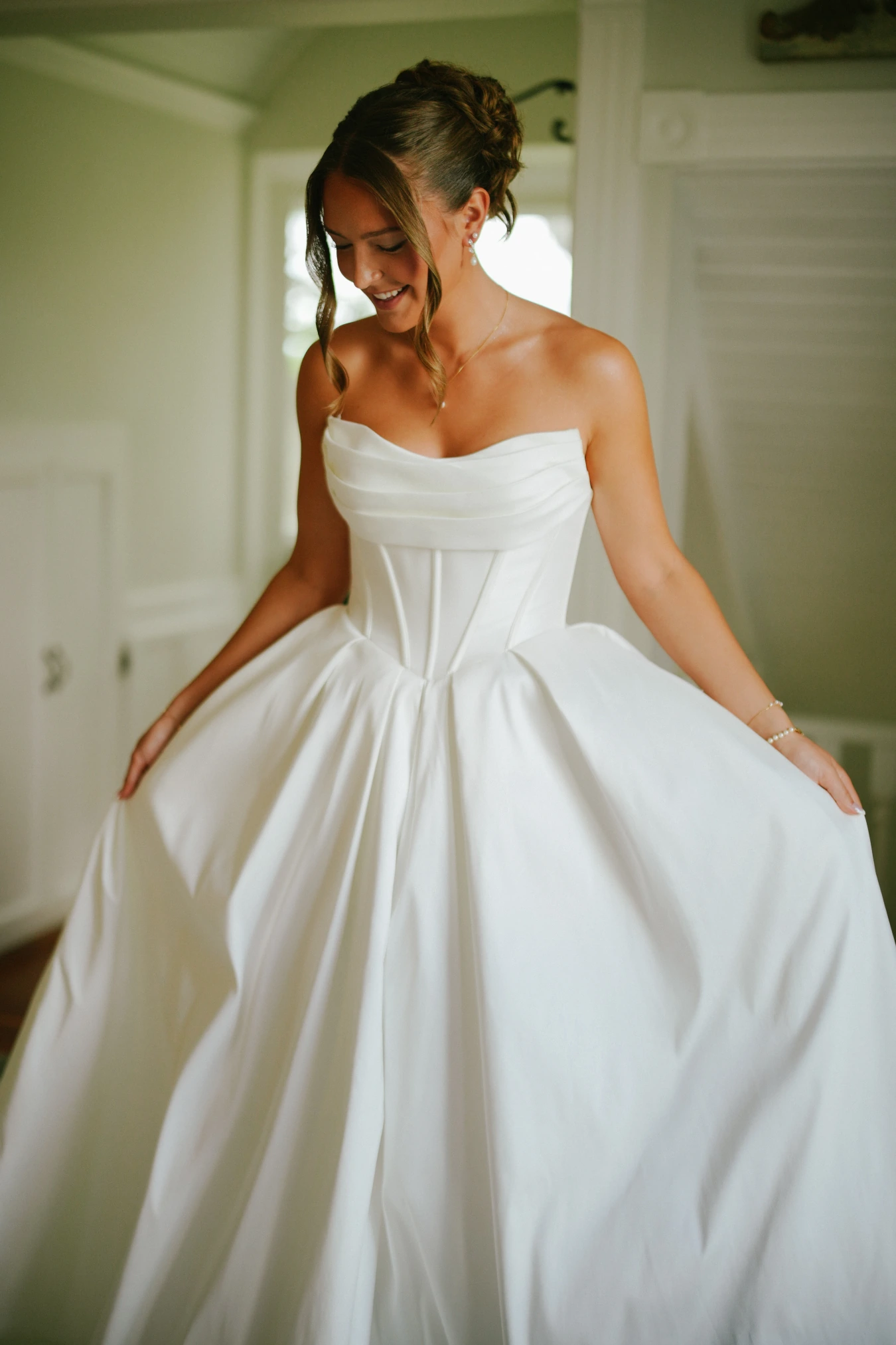 Amy smiling holding dress at Amy and Teddy's North Dakota farm wedding by Megaset Weddings