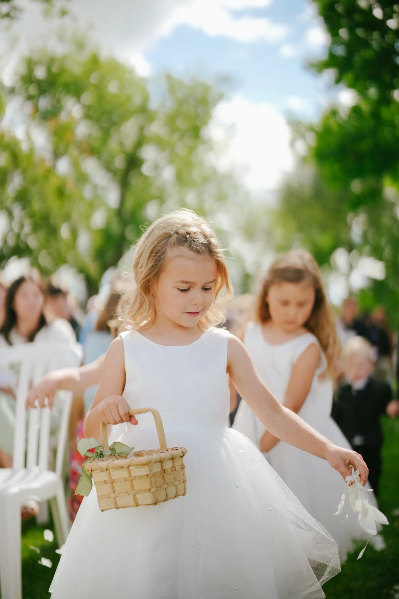 Flower girls walking aisle baskets at Amy and Teddy's North Dakota farm wedding by Megaset Weddings