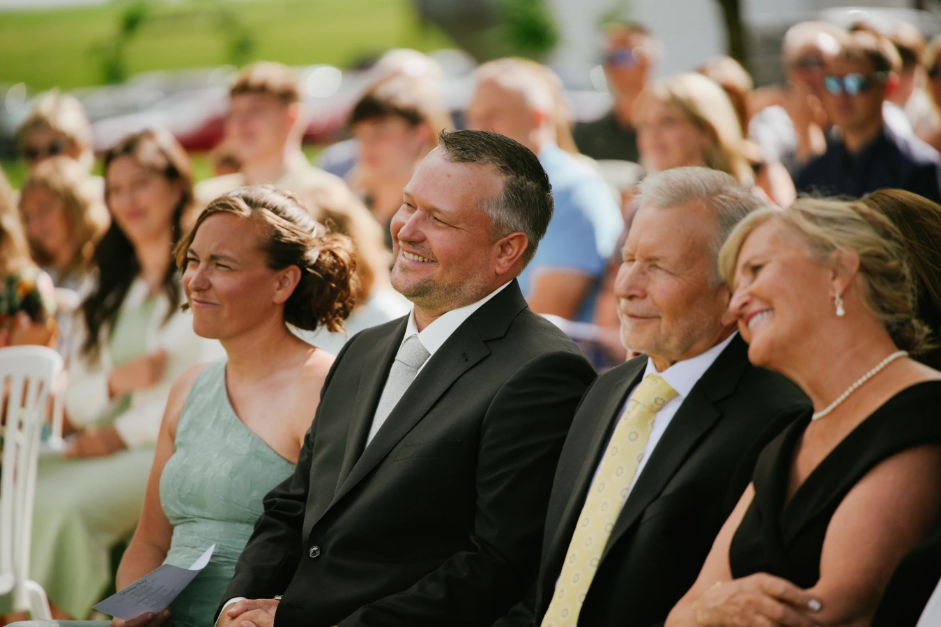 Guests smiling outdoor ceremony at Amy and Teddy's North Dakota farm wedding by Megaset Weddings