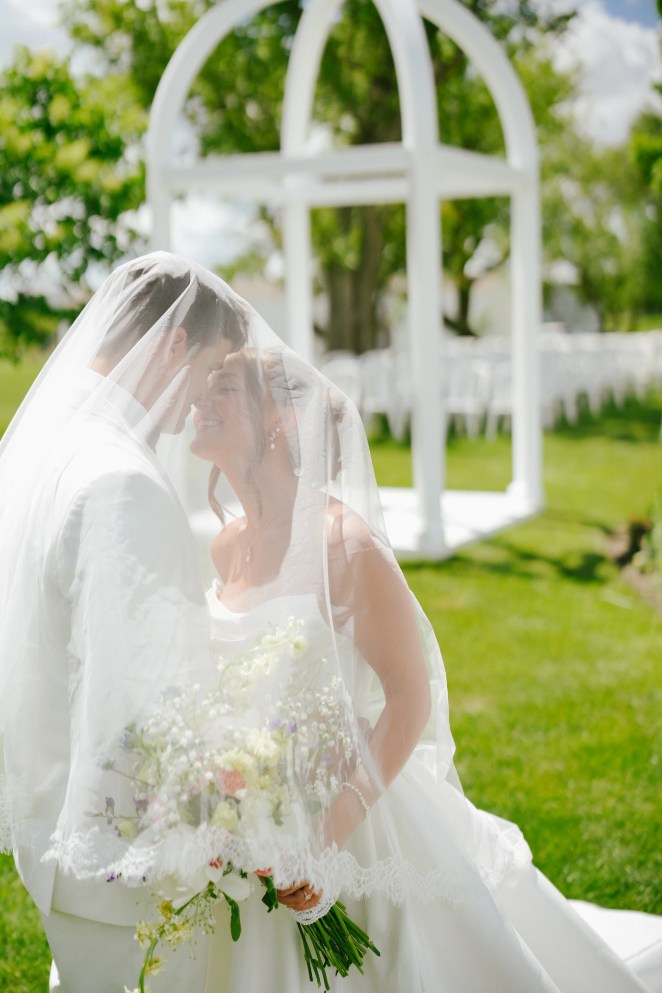 Amy and teddy kiss outdoor arch at Amy and Teddy's North Dakota farm wedding by Megaset Weddings