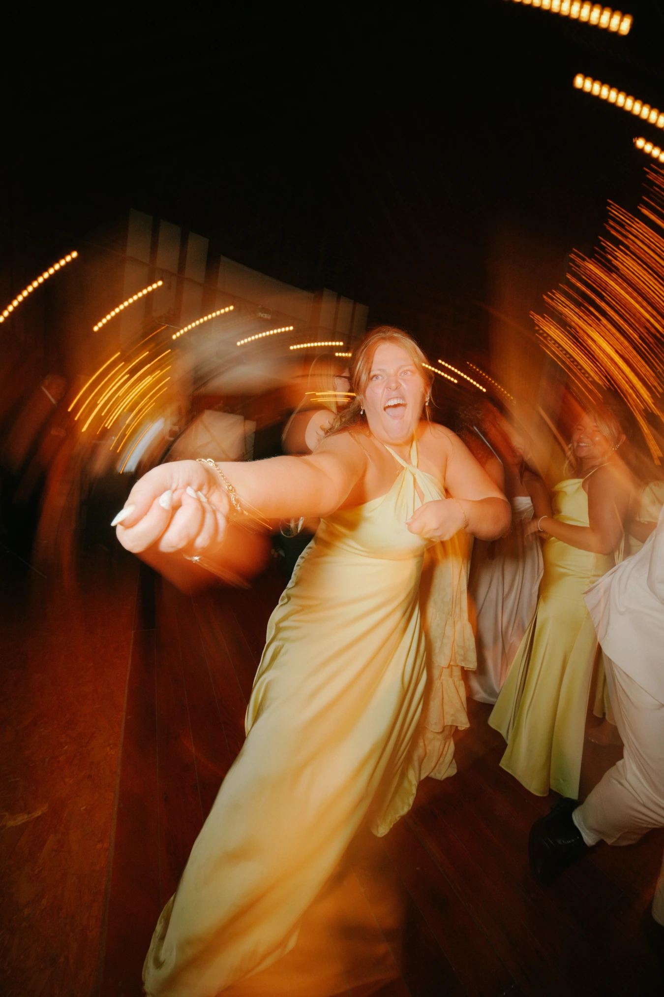 Woman yellow dress dancing joy blurred motion at Amy and Teddy's North Dakota farm wedding by Megaset Weddings