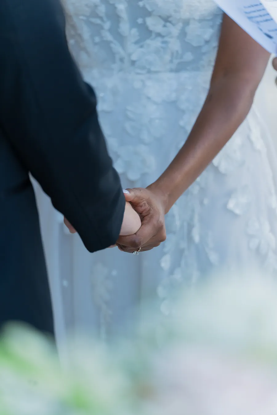Close detail of Belinda and Kevin holding hands during the ceremony